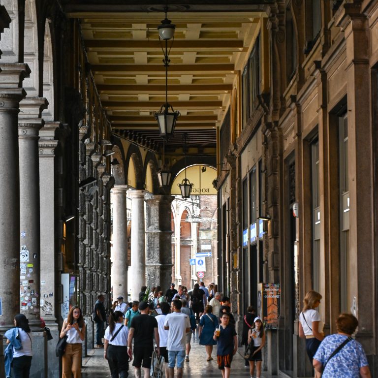 Locals and tourists alike walking through the porticos in Bologna, Italy